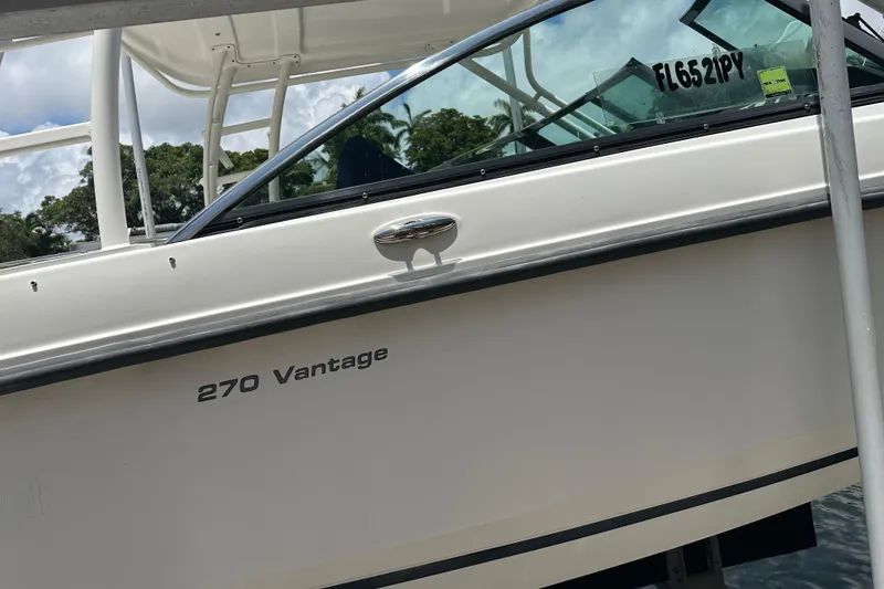 Slide: The Image of 2015 Boston Whaler 270 Vantage boat docked, showcasing sleek design and registration number. - 10