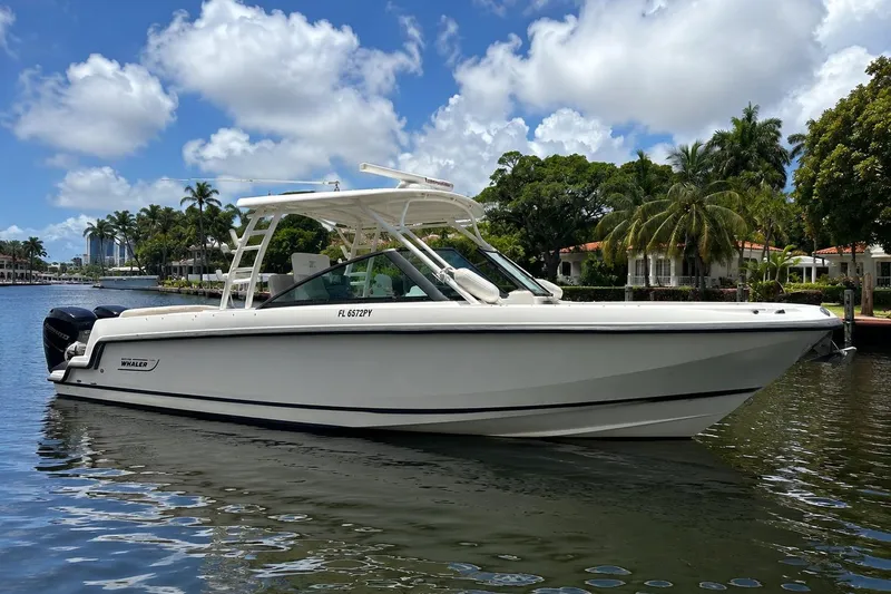 Slide: The Image of 2015 Boston Whaler 270 Vantage boat on calm water, surrounded by lush greenery. - 38