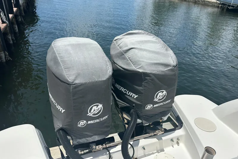 Slide: The Image of Covered Mercury outboard motors on a 2015 Boston Whaler 270 Vantage, docked by the water. - 16