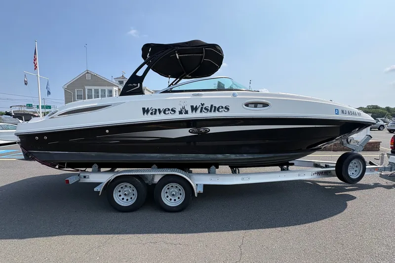 Slide: The Image of 2014 Sea Ray 260 Sundeck boat named "Waves Wishes" on a trailer in a marina. - 1