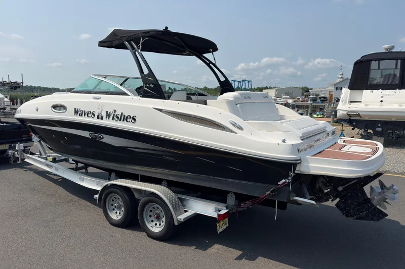 Slide: The Image of 2014 Sea Ray 260 Sundeck boat named "Waves Wishes" on a trailer at a marina. - 3