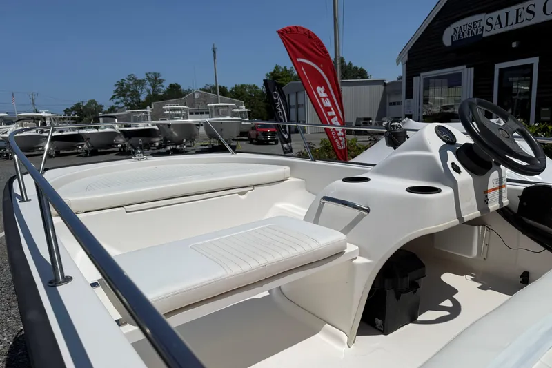 Slide: The Image of 2008 Boston Whaler 150 Sport boat interior at a sales center, showcasing seating and steering console. - 6