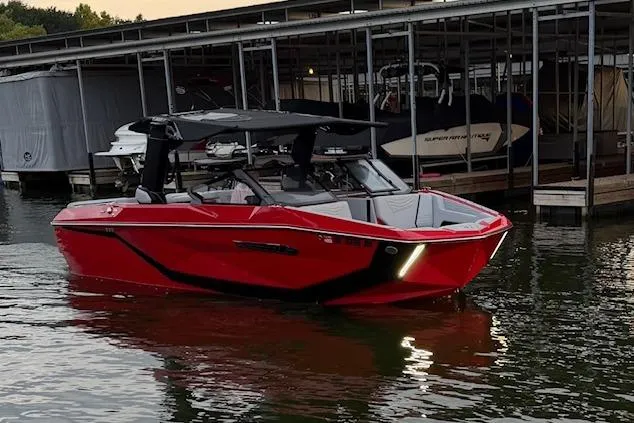 Slide: The Image of 2025 Nautique Super Air Nautique G23 boat, red, docked in marina at dusk. - 5