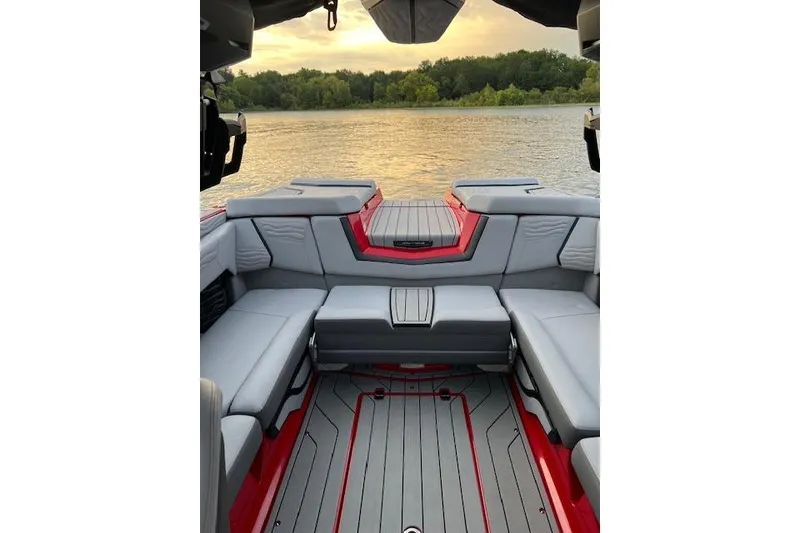 Slide: The Image of 2025 Nautique Super Air Nautique G23 boat interior with gray seating and red accents on a lake. - 13
