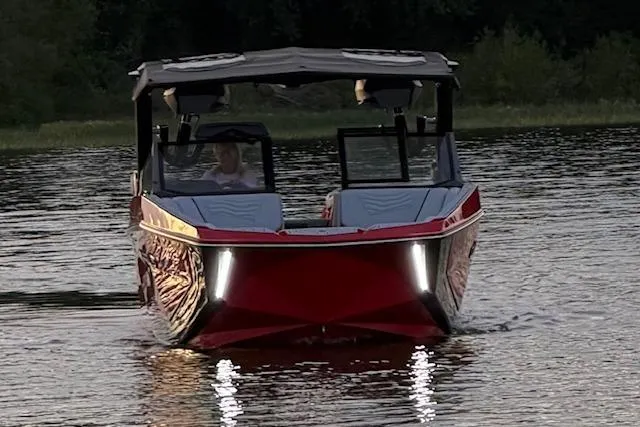 Slide: The Image of 2025 Nautique Super Air Nautique G23 boat on water, front view, with LED lights. - 2