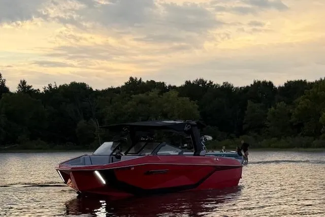 Slide: The Image of 2025 Nautique Super Air Nautique G23 boat on a serene lake at sunset. - 3