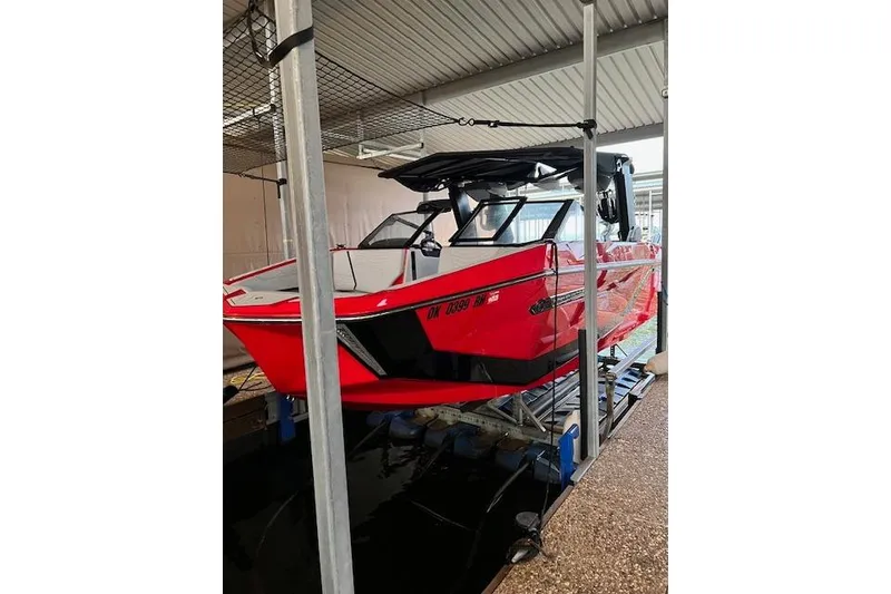 Slide: The Image of 2025 Nautique Super Air Nautique G23 boat in vibrant red, docked indoors. - 8