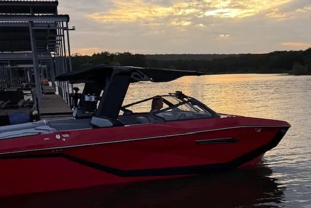 Slide: The Image of 2025 Nautique Super Air Nautique G23 boat docked at sunset on a serene lake. - 15