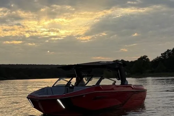 Slide: The Image of 2025 Nautique Super Air Nautique G23 boat on a serene lake at sunset. - 16