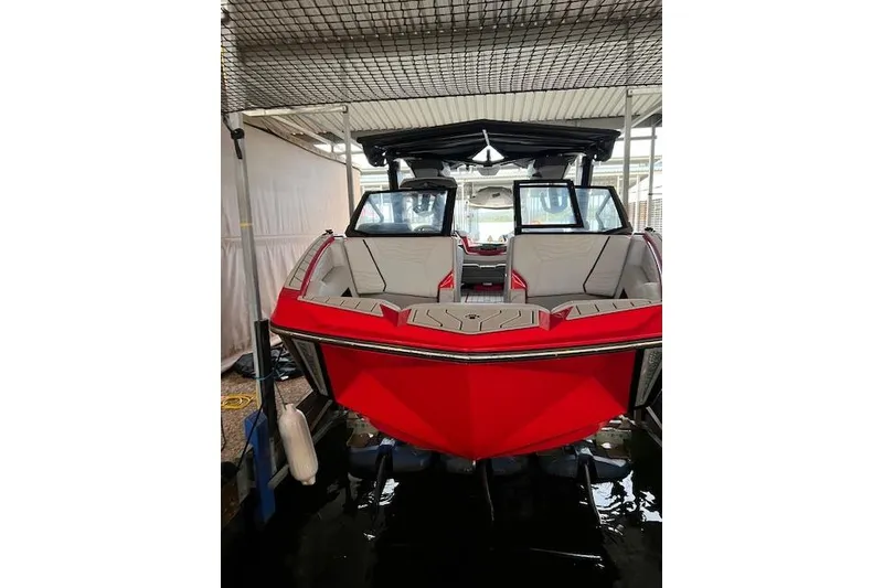 Slide: The Image of 2025 Nautique Super Air Nautique G23 boat in vibrant red, docked indoors. - 7