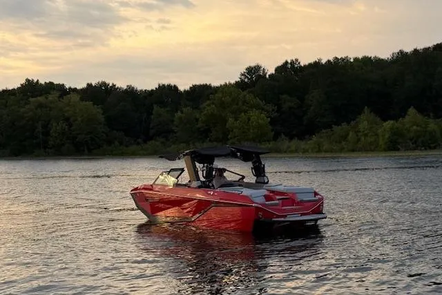 Slide: The Image of 2025 Nautique Super Air Nautique G23 boat on a serene lake at sunset. - 4