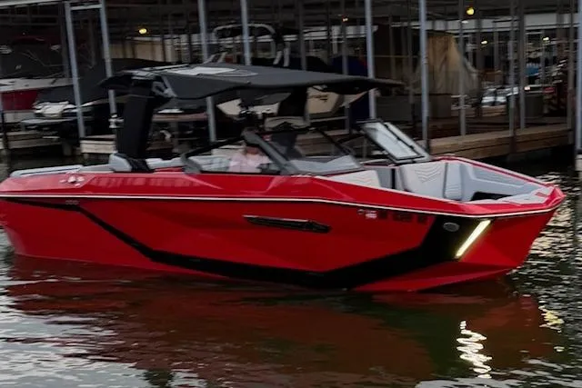 The Image of 2025 Nautique Super Air Nautique G23 boat in vibrant red, docked at a marina. - 0