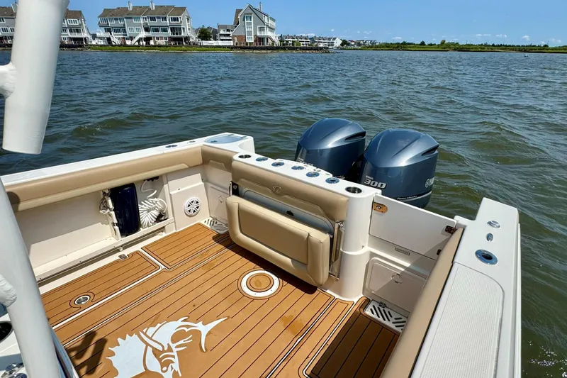 Slide: The Image of 2017 Sailfish 290 CC boat with twin engines, teak deck, and waterfront view. - 23