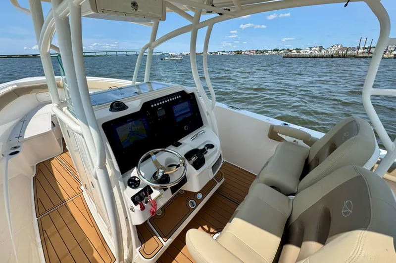 Slide: The Image of 2017 Sailfish 290 CC boat interior with dual seats, steering wheel, and navigation screens on open water. - 11