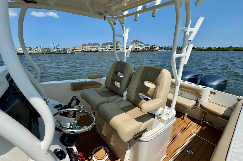 Slide: The Image of 2017 Sailfish 290 CC boat interior with beige seating, steering wheel, and ocean view. - 18