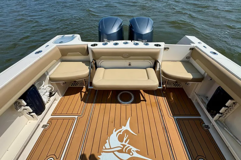 Slide: The Image of 2017 Sailfish 290 CC boat interior with cushioned seating and twin outboard motors. - 24