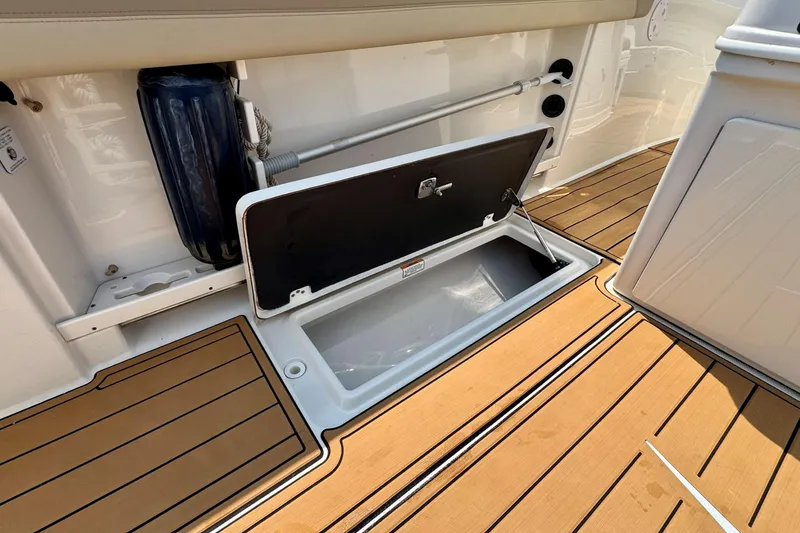 Slide: The Image of Open storage compartment on 2017 Sailfish 290 CC boat with teak flooring. - 26