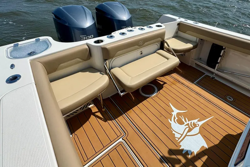 Slide: The Image of 2017 Sailfish 290 CC boat interior with tan seating, wooden deck, and twin Yamaha 300 engines. - 28