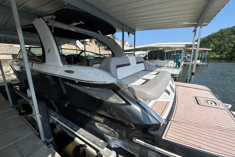 Slide: The Image of 2017 Four Winns H290 boat docked under a covered marina, featuring sleek black and white design. - 3