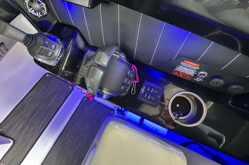 Slide: The Image of 2017 Four Winns H290 boat cockpit with controls, cup holder, and blue ambient lighting. - 9