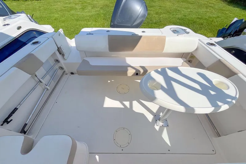 Slide: The Image of 2019 Robalo R247 Dual Console boat interior with seating and table, set against a grassy background. - 5