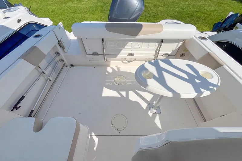 Slide: The Image of 2019 Robalo R247 Dual Console boat interior with seating and round table on deck. - 4