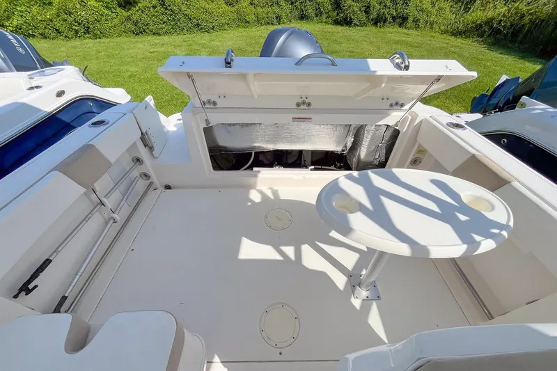 Slide: The Image of 2019 Robalo R247 Dual Console boat interior with seating and table, open storage compartment. - 6