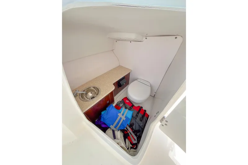 Slide: The Image of 2019 Robalo R247 Dual Console boat interior with sink, toilet, and life jackets. - 11