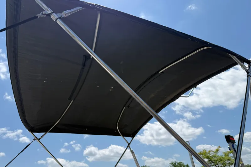 Slide: The Image of 2014 Hurricane SunDeck Sport 188 OB bimini top against a blue sky with clouds. - 28