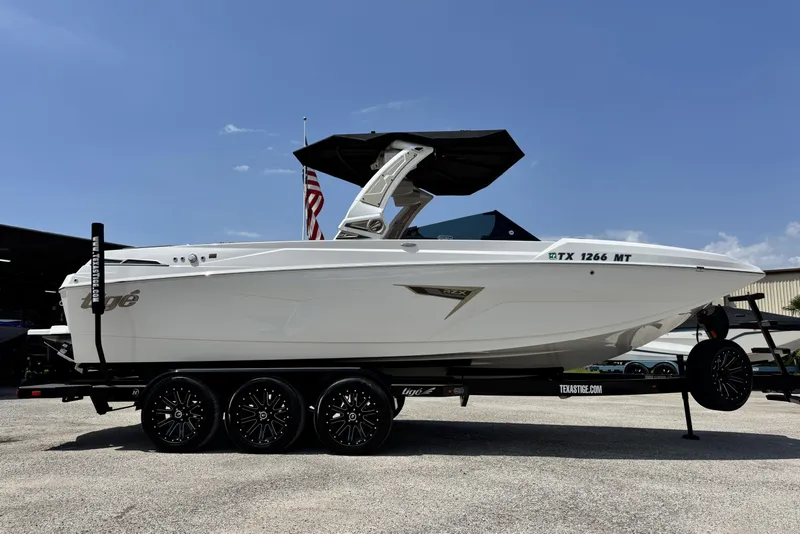 Slide: The Image of 2025 Tigé 24RZX boat on trailer, sleek design, white exterior, under clear blue sky. - 3