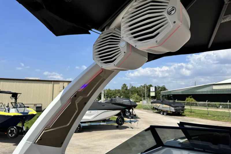 Slide: The Image of 2025 Tigé 24RZX boat with mounted speakers, docked under a clear sky. - 18