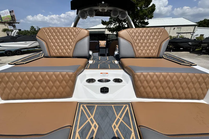 Slide: The Image of 2025 Tigé 24RZX boat interior with luxurious brown diamond-stitched seating under a sunny sky. - 21