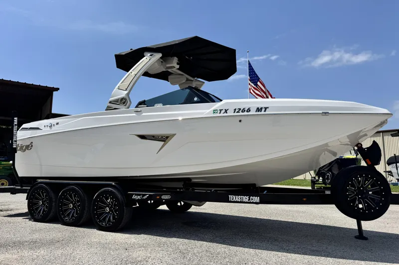 The Image of 2025 Tigé 24RZX boat on trailer, sleek design, American flag in background. - 1