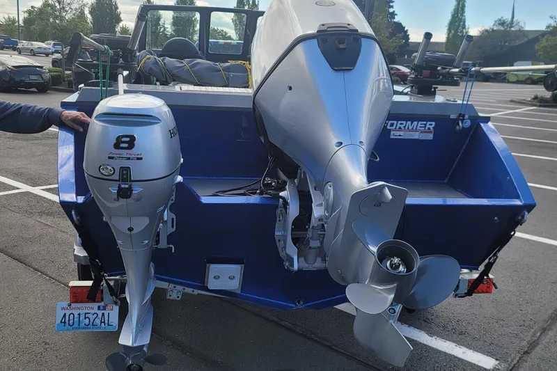 Slide: The Image of 2023 Fish Rite 210 Performer boat with dual outboard motors in a parking lot. - 11