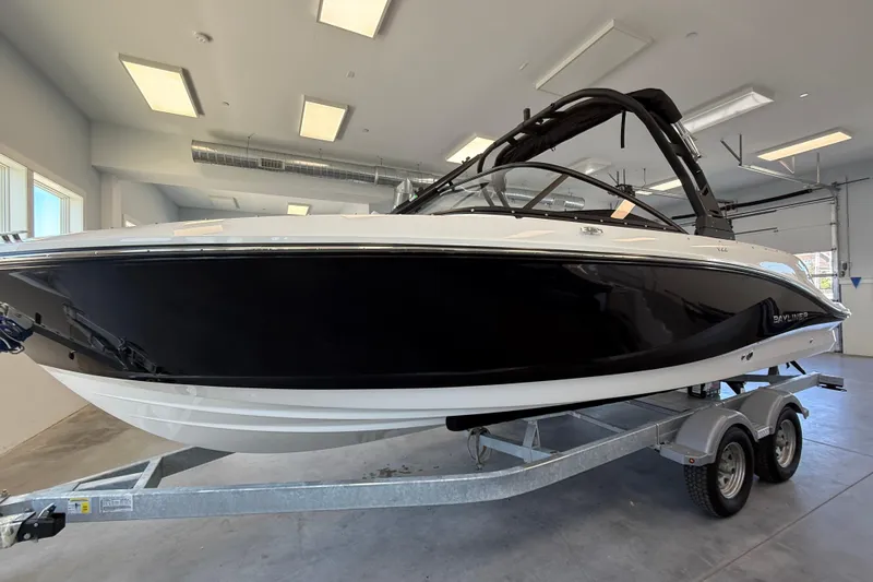 Slide: The Image of 2026 Bayliner V22 boat on trailer in showroom, sleek black and white design. - 2