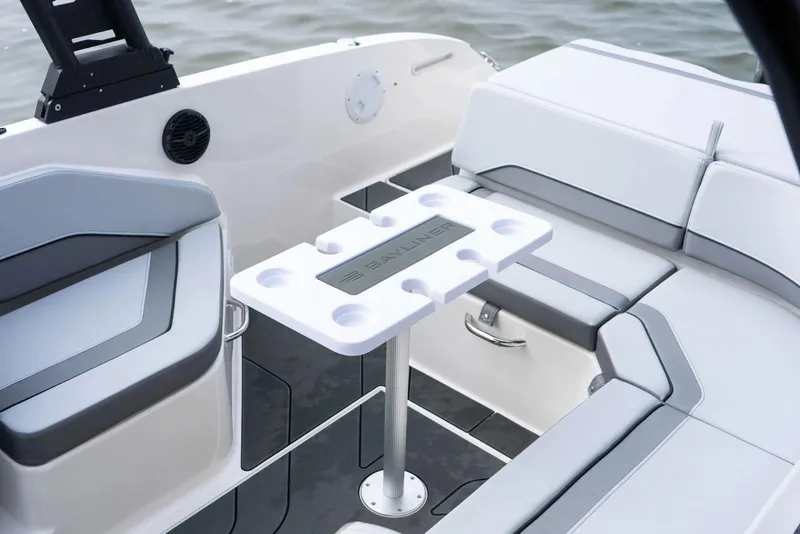 Slide: The Image of Manufacturer Provided Image: 2026 Bayliner V22 boat interior with seating and a central table on the water. - 12