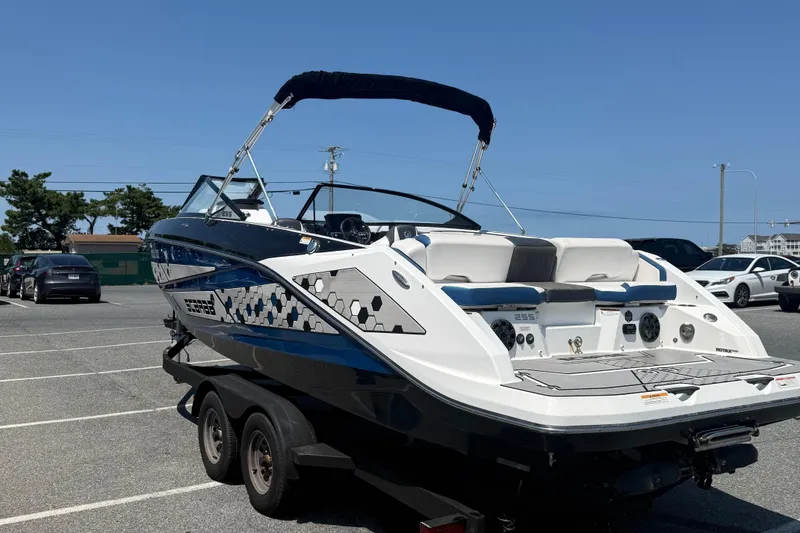 Slide: The Image of 2020 Scarab 255 Open ID boat on trailer in parking lot under clear blue sky. - 6