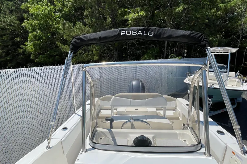 Slide: The Image of 2018 Robalo R180 Center Console boat with canopy, parked near a fence. - 12