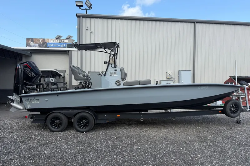 The Image of 2027 Skuta 24 Cat boat on trailer, parked outside a warehouse. - 0