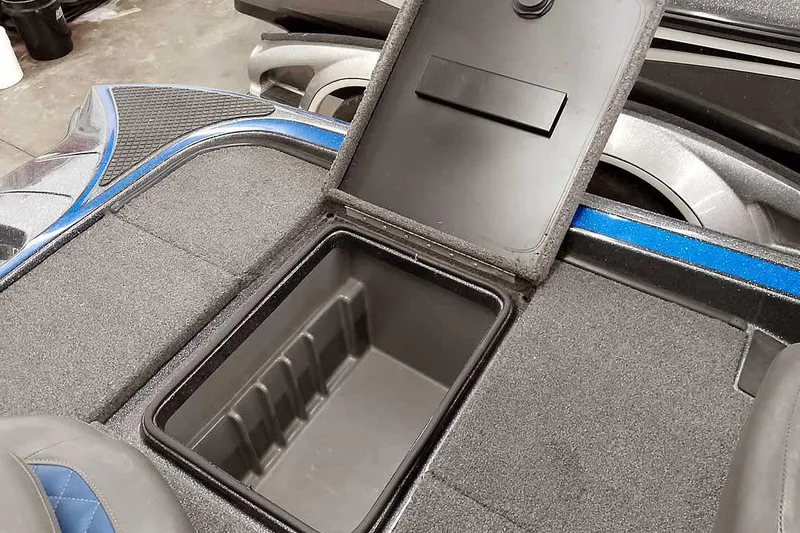 Slide: The Image of Open storage compartment on a 2015 Triton 19 TrX boat, featuring carpeted interior. - 32