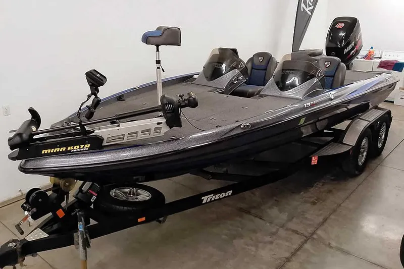 The Image of 2015 Triton 19 TrX bass boat with Minn Kota trolling motor on trailer in garage. - 0