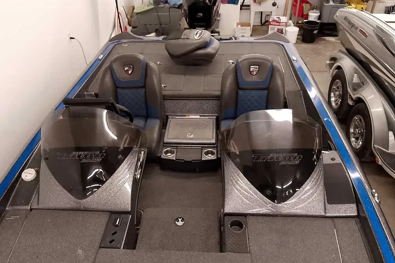 Slide: The Image of 2015 Triton 19 TrX boat interior with dual consoles and blue-accented seats in a garage. - 24