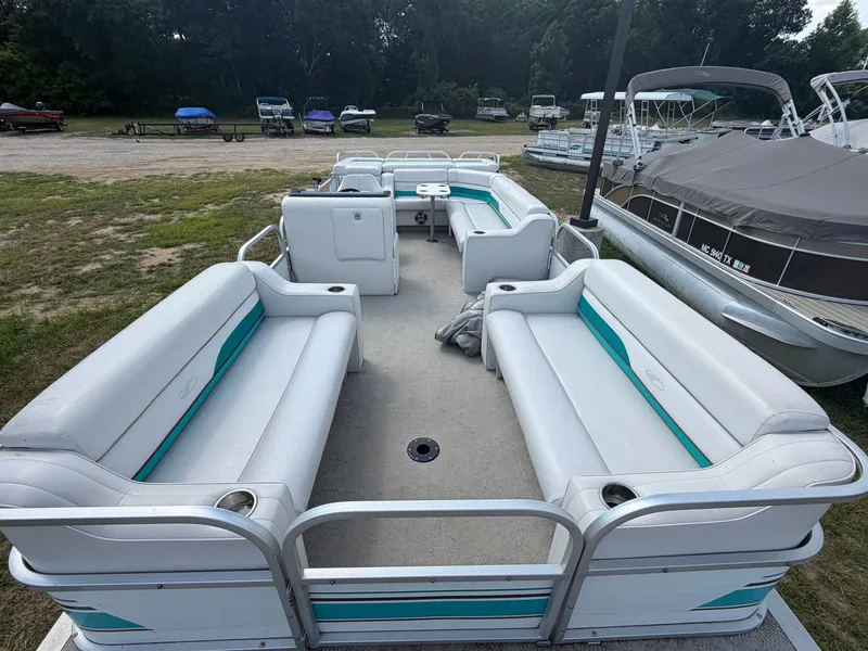 Slide: The Image of A 1994 Starcraft 240 Stardeck Pontoon with white and teal seating, parked on grass. - 3