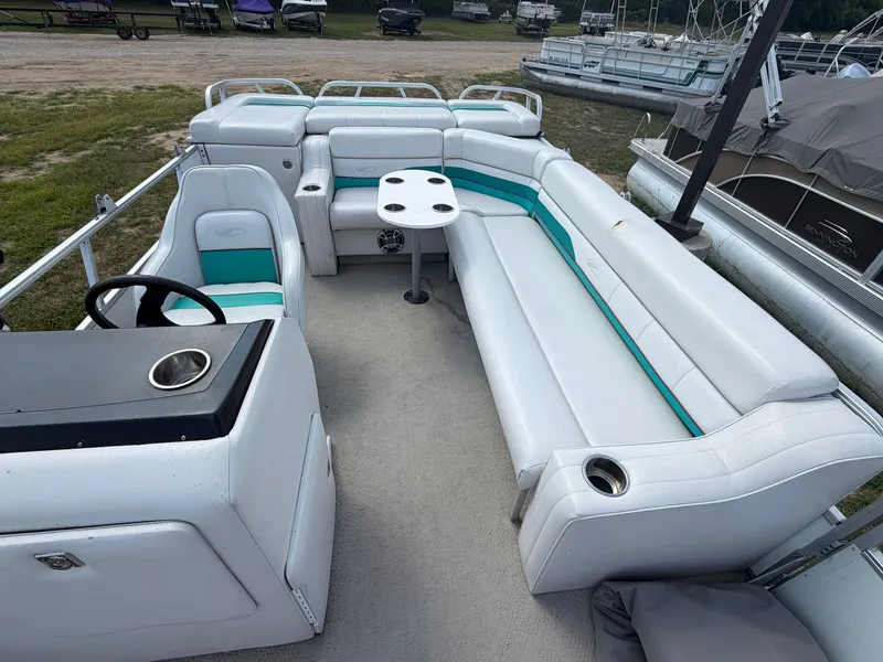 Slide: The Image of A spacious pontoon boat with white and teal seating, a table, and a helm station. - 4