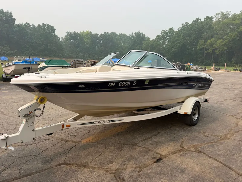 Slide: The Image of A white 2005 Sea Ray 185 Sport boat on a trailer, surrounded by trees. - 5