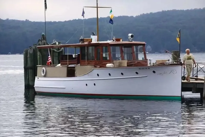 Slide: The Image of A classic 1926 Hubert Johnson 43' cruiser docked in a serene setting. - 3