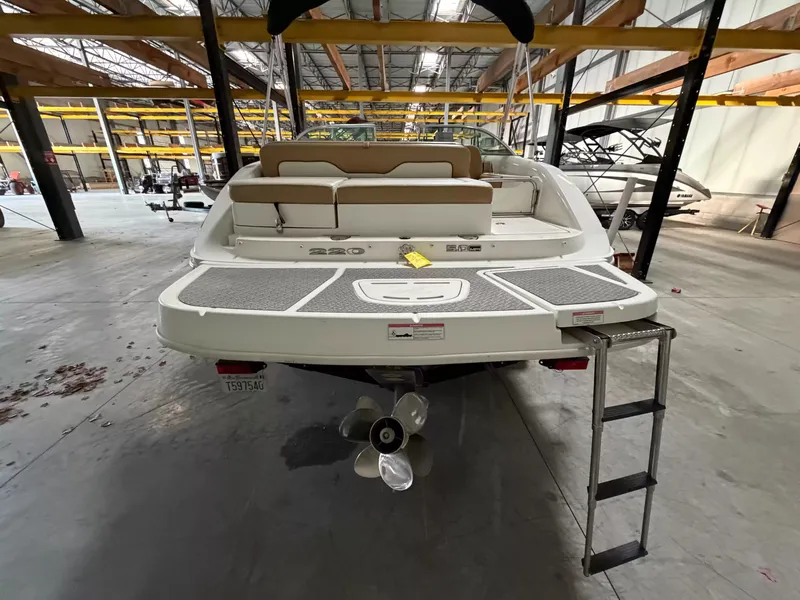 Slide: The Image of A 2011 Sea Ray 220 Sundeck in a warehouse. It features a swim platform and ladder. - 4