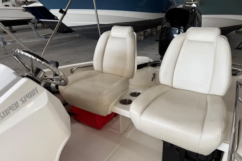 Slide: The Image of 2021 Boston Whaler 130 Super Sport interior with white seats and steering wheel. - 10