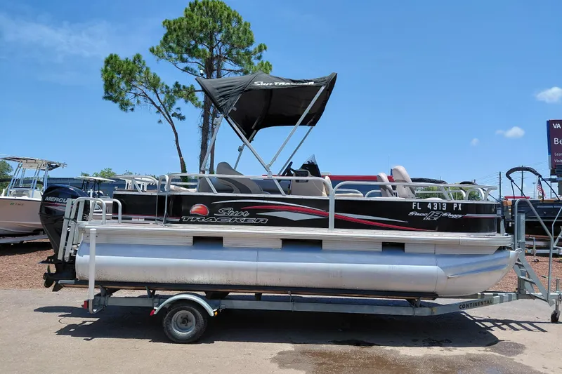 The Image of 2015 Sun Tracker Bass Buggy 18 DLX pontoon boat on trailer, under clear blue sky. - 1