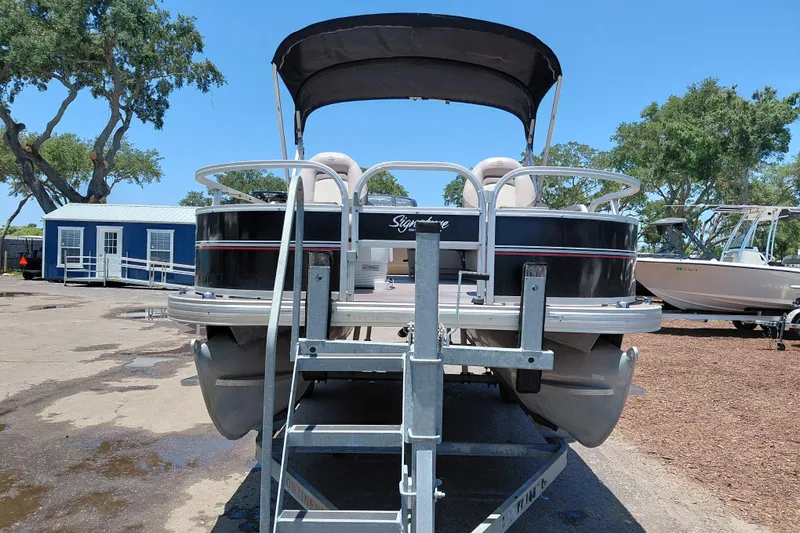 Slide: The Image of 2015 Sun Tracker Bass Buggy 18 DLX pontoon boat on trailer, parked outdoors. - 3